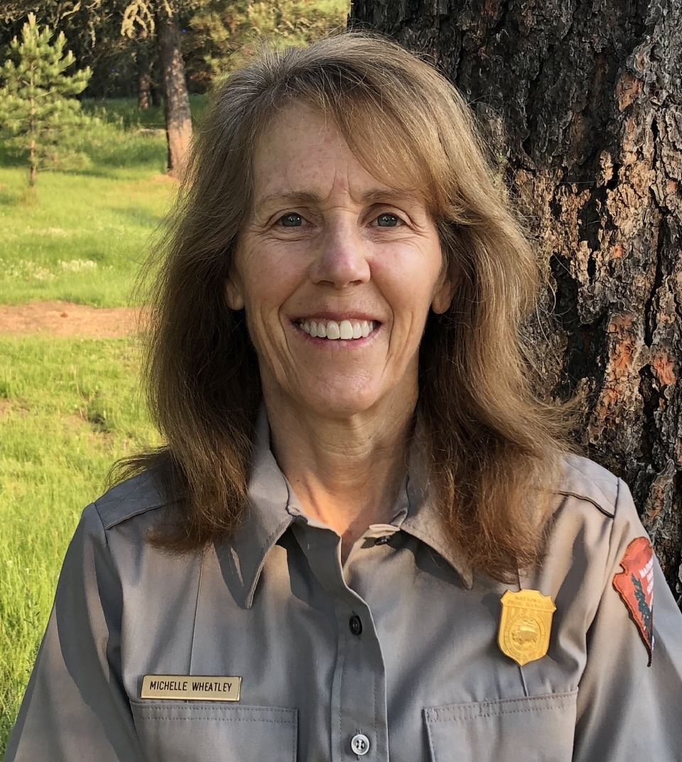 Female park ranger, Michelle Wheatley, in uniform looking at camera with a tree in the background. Female park ranger, Michelle Wheatley, in uniform looking at camera with a tree in the background.