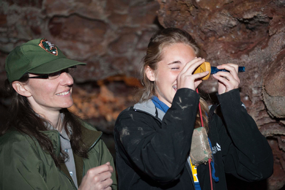 A park employee looks over the shoulder of a student reading a clinometer while in Wind Cave.