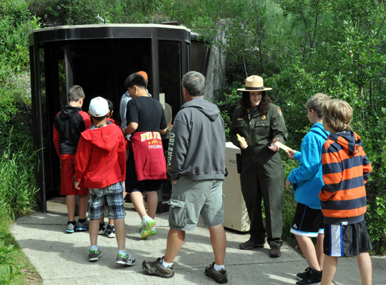 A ranger collects tickets as a people enter the revolving door airlock into Wind Cave.