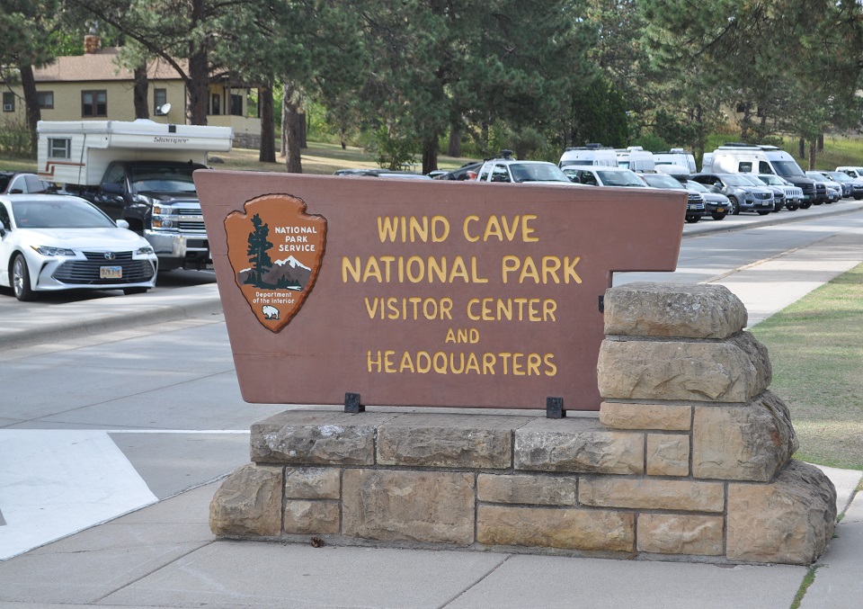 Brown wooden sign on a stone base saying Wind Cave National Park Visitor Center and Headquarters Brown wooden sign on a stone base saying Wind Cave National Park Visitor Center and Headquarters