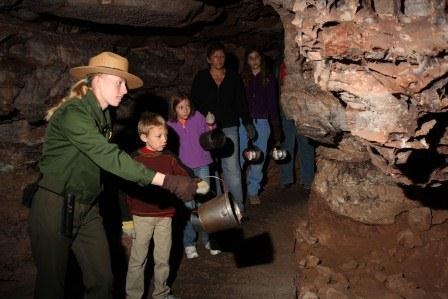A ranger-led tour with a family. They are all holding candle buckets. A ranger-led tour with a family. They are all holding candle buckets.
