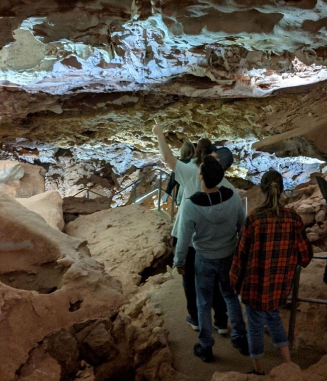 People walking down stairs in a large cave room