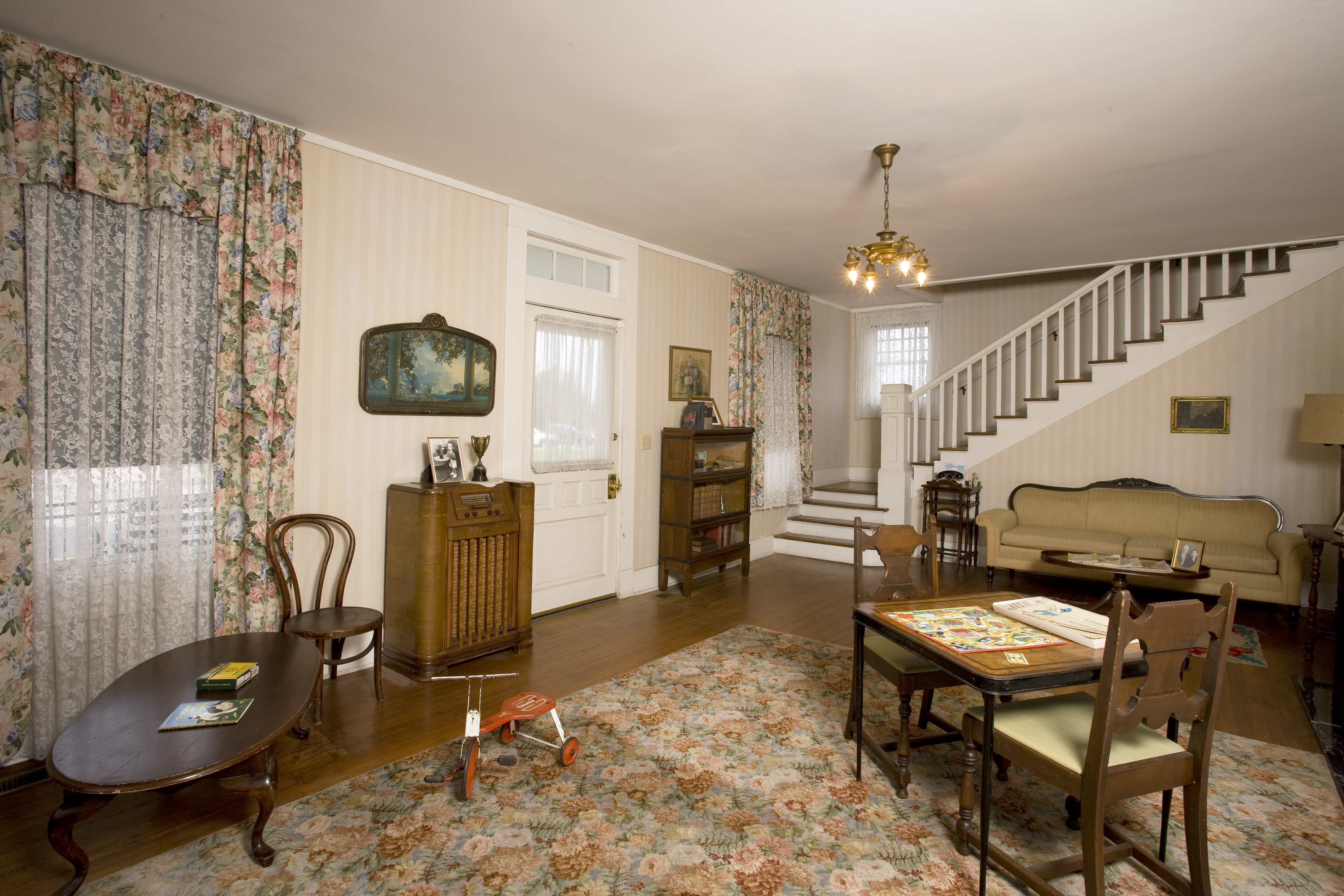 The front entrance inside the Birthplace Home contains a fireplace, table and chairs, family photos, a telephone and floor console radio.