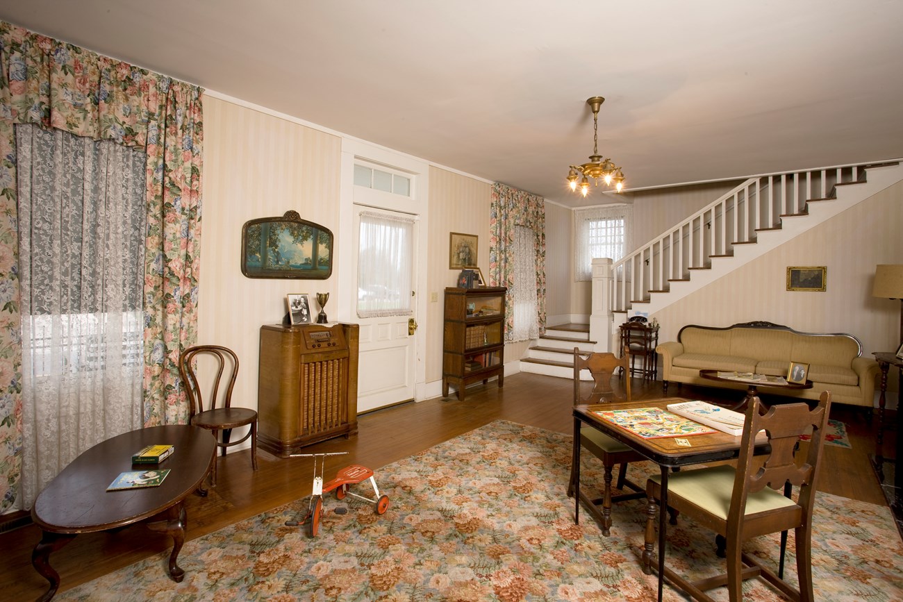 The front entrance inside the Birthplace Home contains a fireplace, table and chairs, family photos, a telephone and floor console radio.