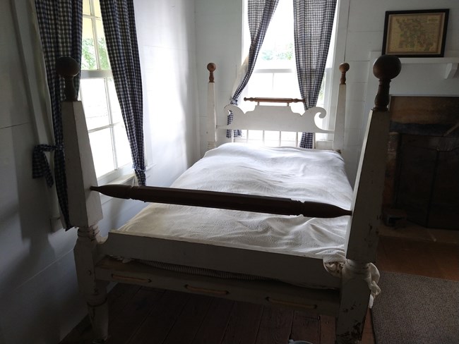 An antique bed is seen inside a historic farm house