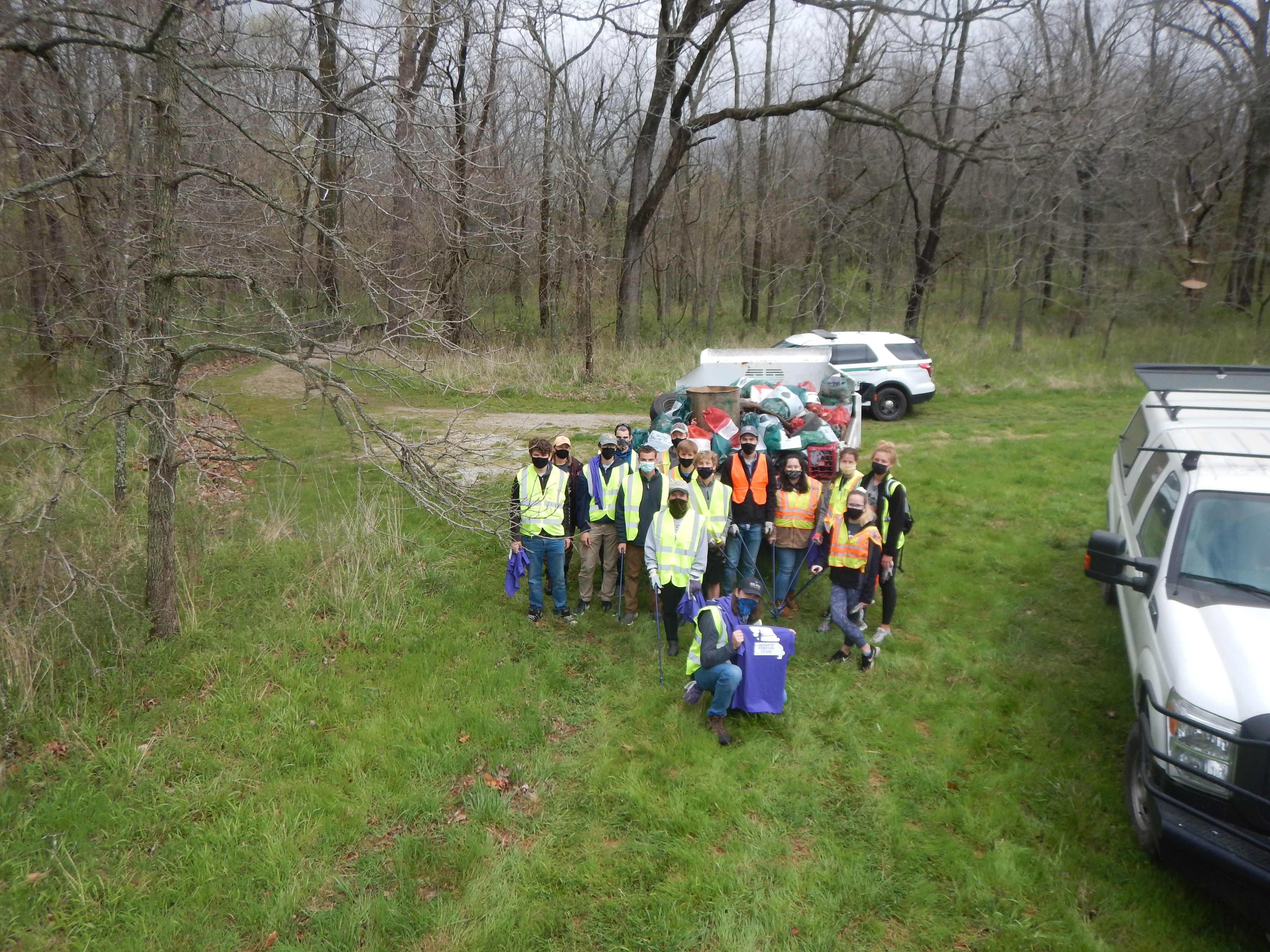 Group picture of volunteers in front of a park truck loaded with trash bags and materials from clean up work day event