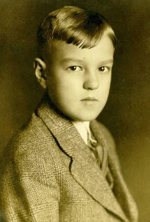A young boy in a suit and tie staring at the camera