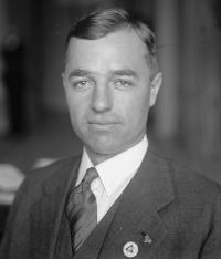 Charles-P-Taft A man in a suit and tie and small white pin on his lapel stares into the camera