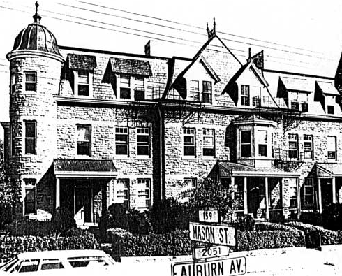 Historic Apt on Cross Prop A large three-story building with towering end columns and cars parked on the street in front