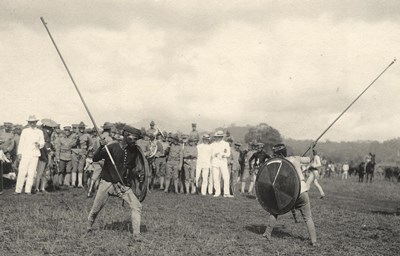 Moro Warriors in Philippines Two indigenous men with spears pointed at each other as spectators look on