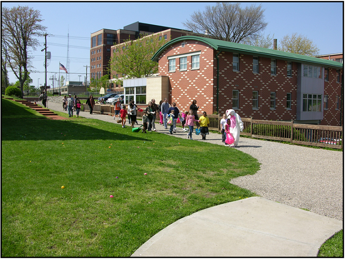 Children at the park follow the Easter Bunny down a path.