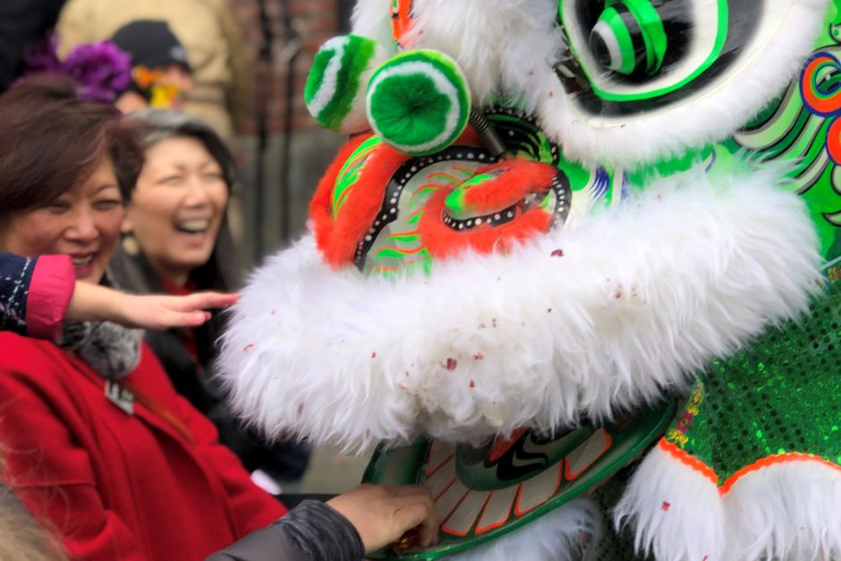 People smile and feed a lion as part of a New Year's lion dance celebration