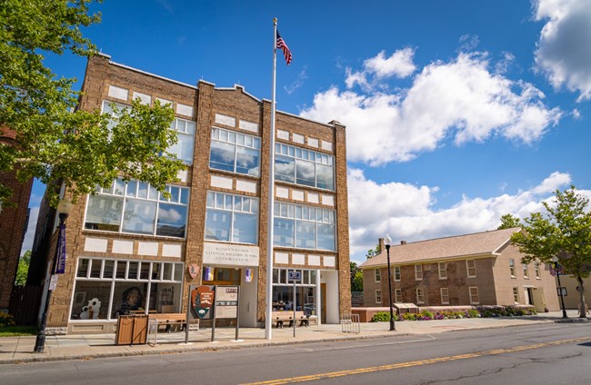 A wide-angle view of a three-story stone building across a street.