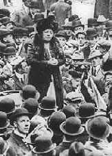 Harriot Stanton Blatch giving a speech in a crowd of men wearing hats.