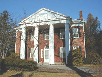 The Hunt House is a two story red brick residence with four decorative white columns and portico on the front.