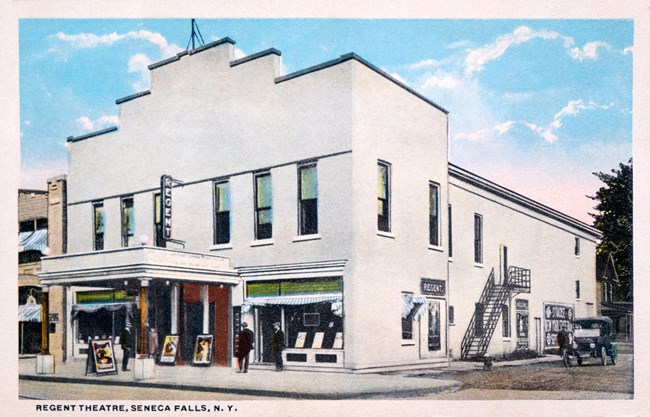 An old postcard of a white movie theater building.