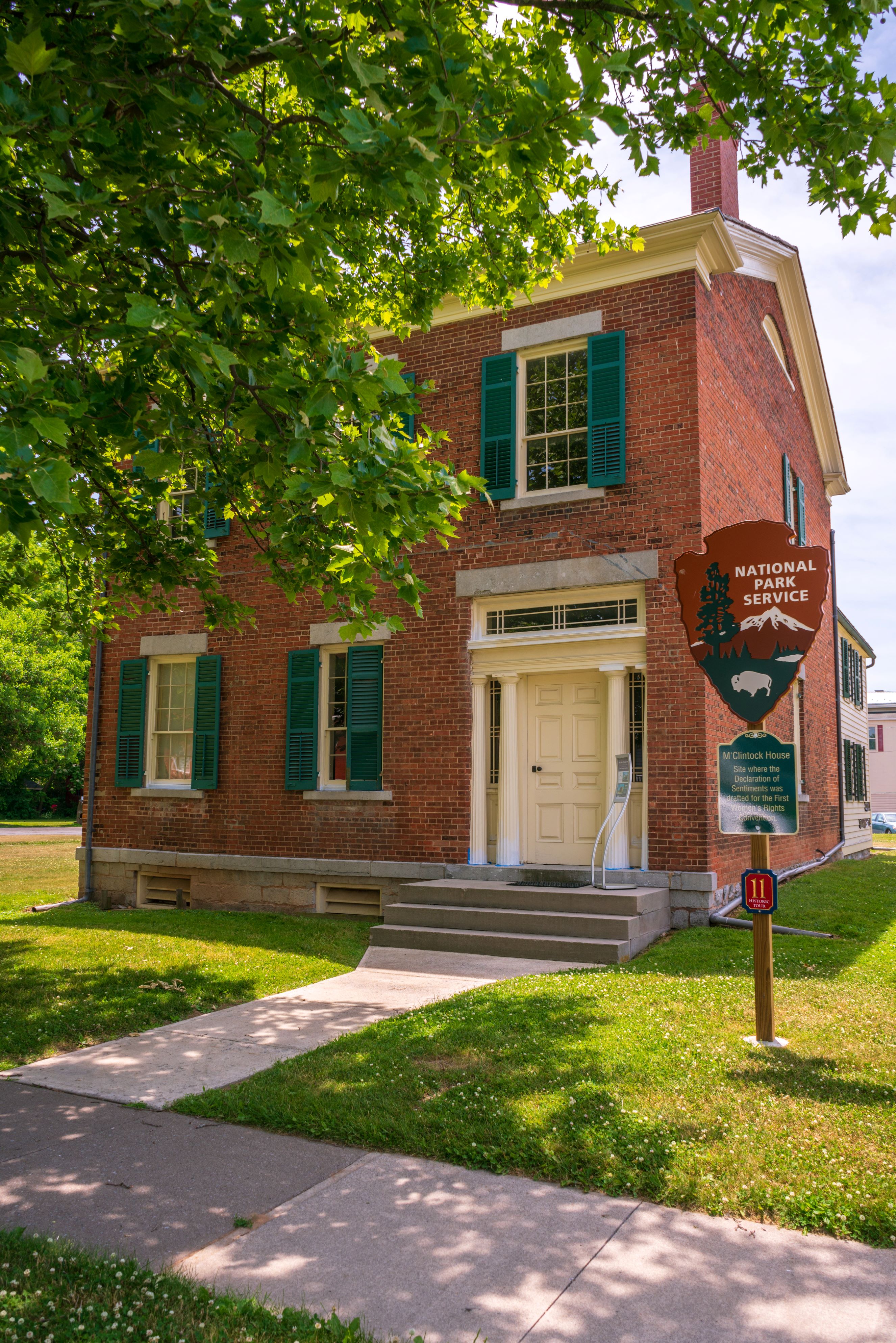 M'Clintock House A two-story red brick building with green shutters and a white door.