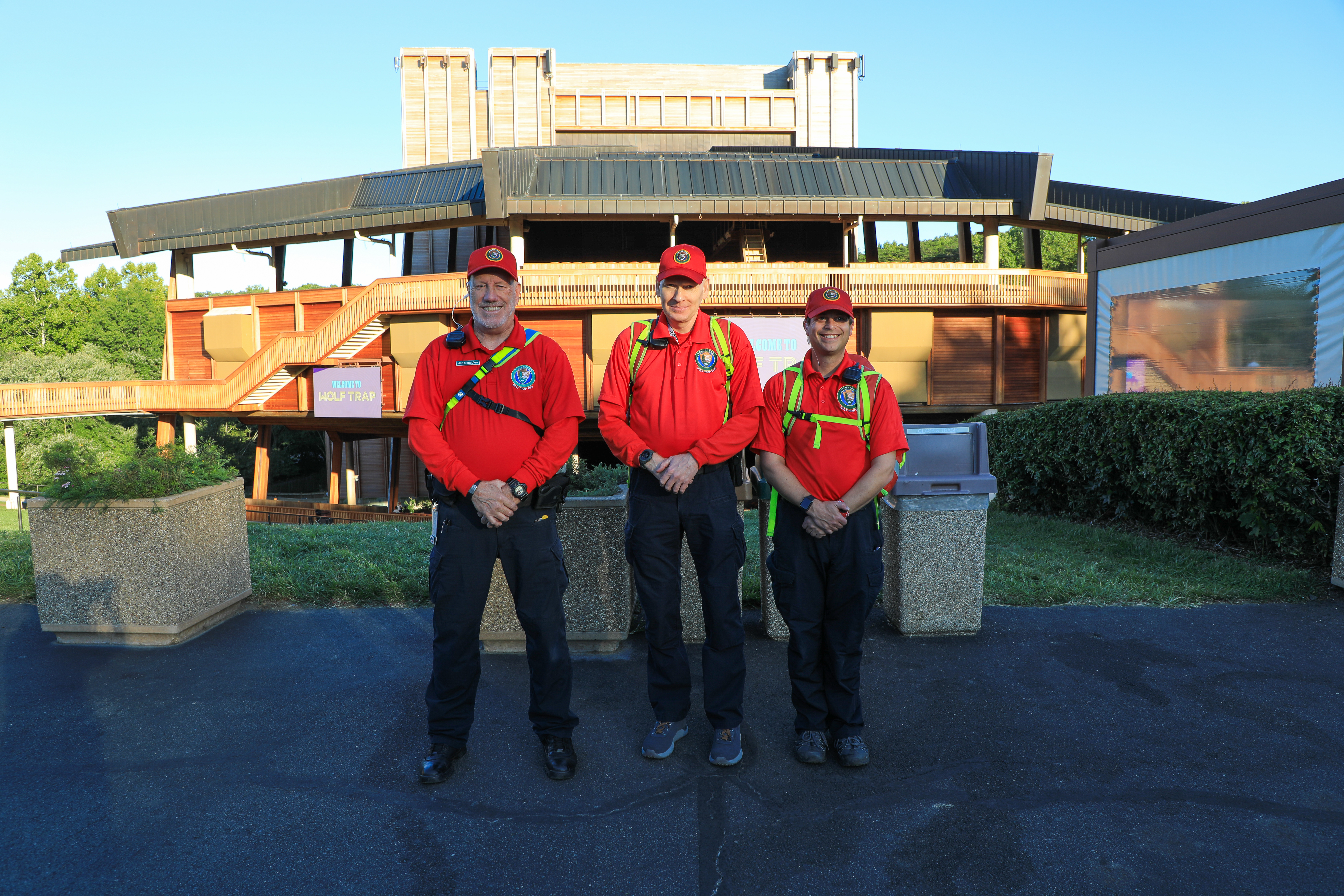 Three volunteers in red shirts in front of the Filene Center