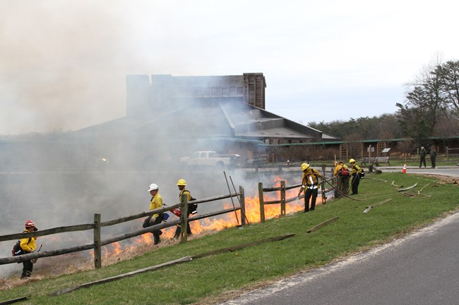 Firefighters burn a meadow in front of the Filene Center entrance.