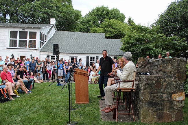 A Pre-Performance Discussion takes place on the Farmhouse Lawn.