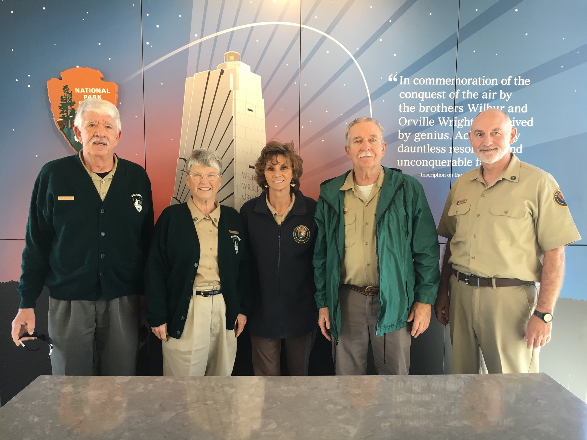 a group of volunteers standing in uniform behind the desk