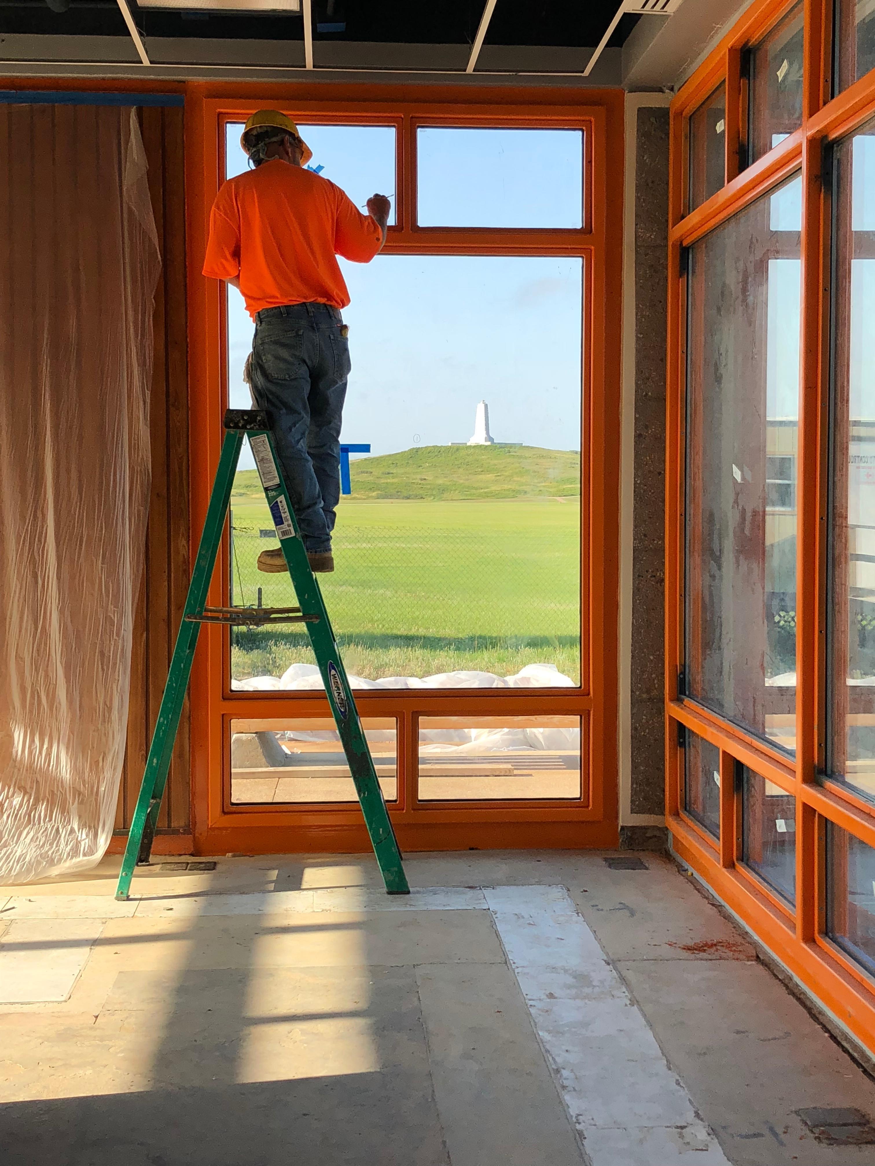 Contractor working on custom fabricated window frame with view of the Wright Brothers National Memorial monument.