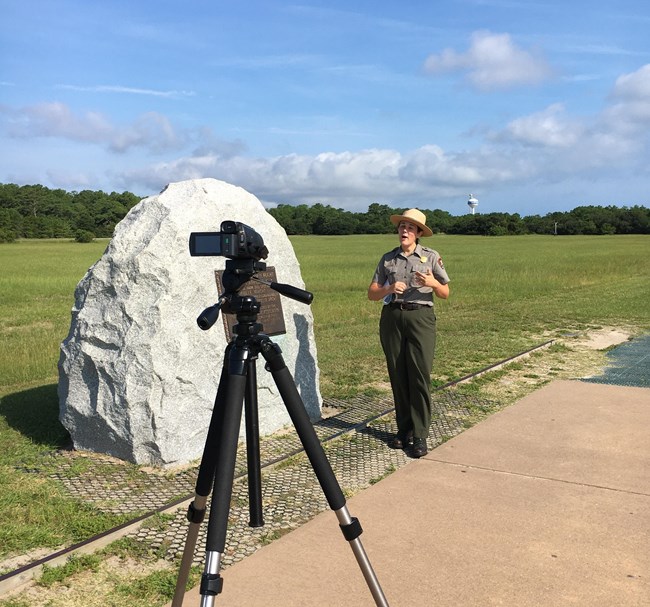 A park ranger stands in front of a video camera