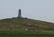 A granite monument stands on top of a grassy hill.