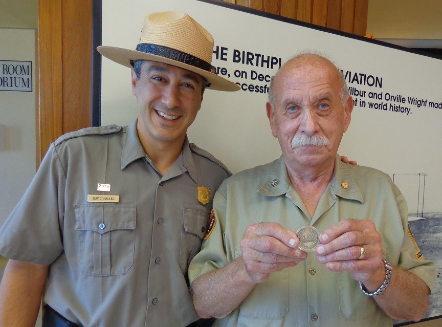 Long-term Wright Brother National Memorial volunteer, Fred Hattman, receives the Centennial Volunteer Challenge Coin from Superintendent David Hallac