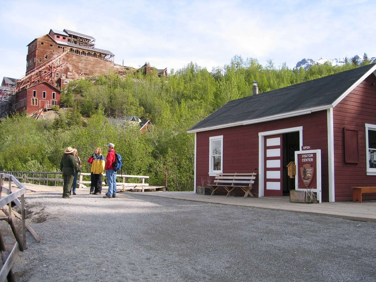 A ranger speaks to visitors at the National Creek bridge. Kennecott Mill in the background.