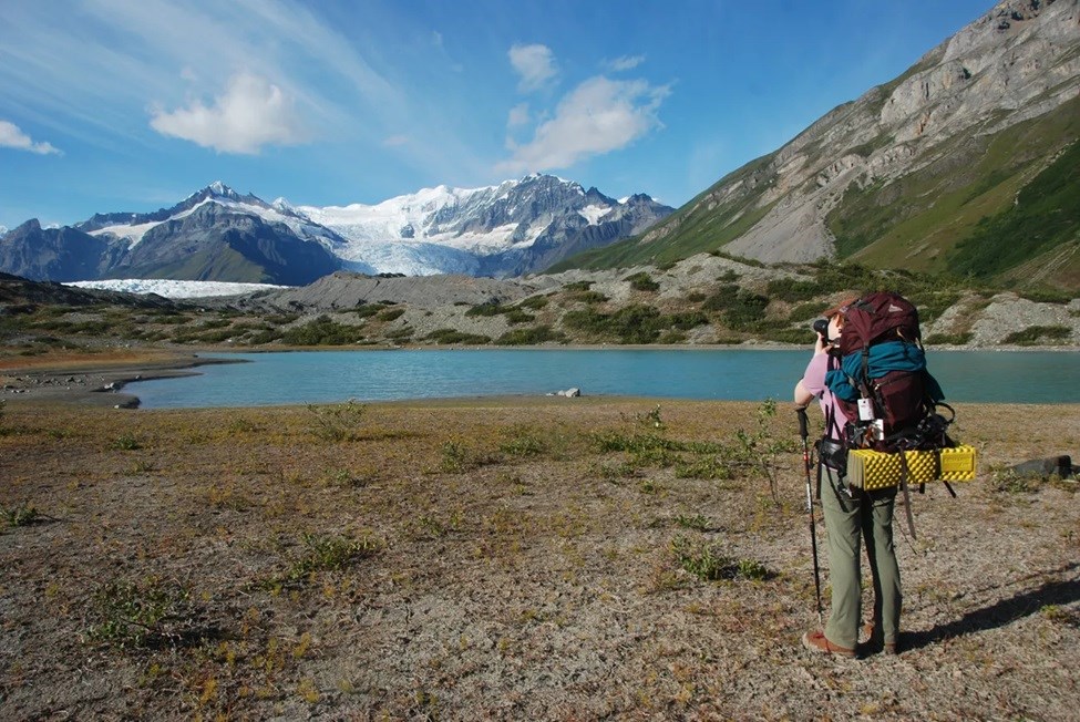 A person taking a photography of a scenic lake and mountain.