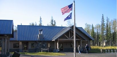 HQVC_top_image.jpg flagpole with american flag and alaska state flag flying in front of a large wood building