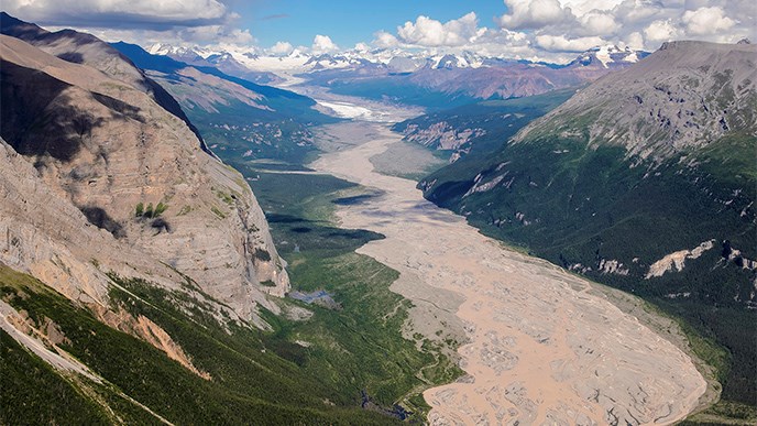 Aerial view of river in deep canyon with mountains in background.