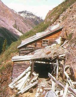 Entrance to abandoned mine on steep mountain slope.