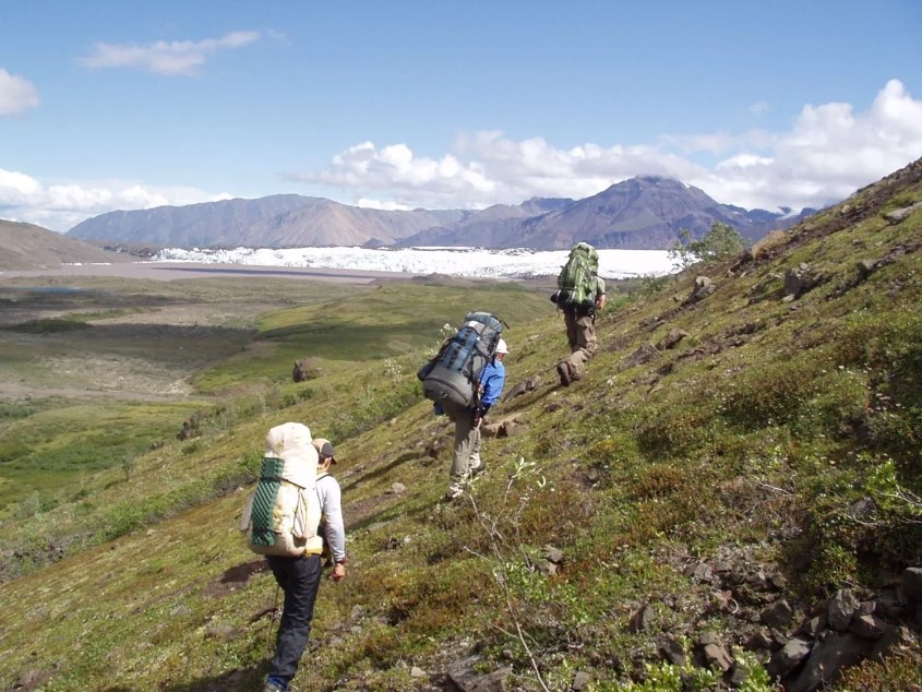 Backpackers hiking along a hillside towards a glacier