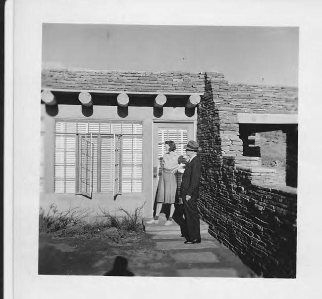 A black and white photo from 1950 of Courtney and Davey Jones in front of the Pueblo Revival stone house.