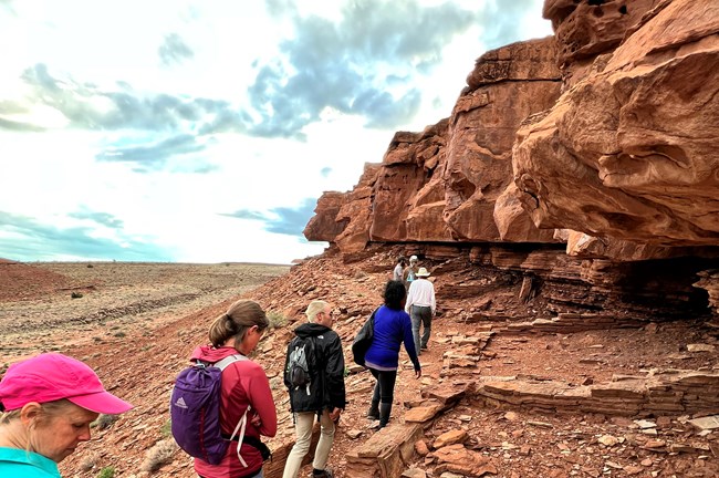 Hikers walk past the footprints of Ancestral Puebloan rooms during a ranger-led hike to the Crack in the Rock pueblo in 2022.