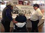 three Navajo women, one in a wheelchair, reading a museum exhibit panel three Navajo women, one in a wheelchair, reading a museum exhibit panel