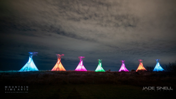 a series of lighted teepees on a hilltop