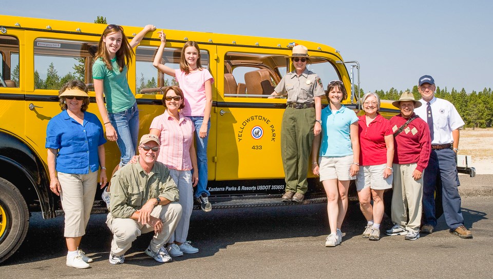 Photo of park and partner employees alongside an historic Yellow Bus