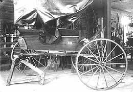 (YELL 41295) Two-seat surrey very similar to the vehicle in the park's museum collection. The vehicle appears to be in the blacksmith's shop for repairs to one of the wheels.