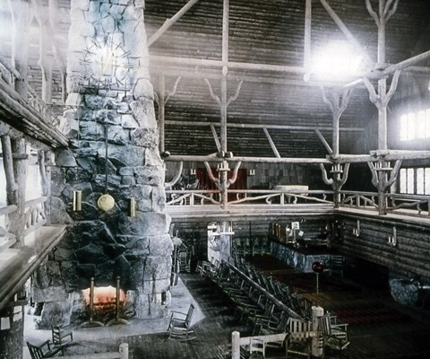 A tall stone fireplace in an open log lobby