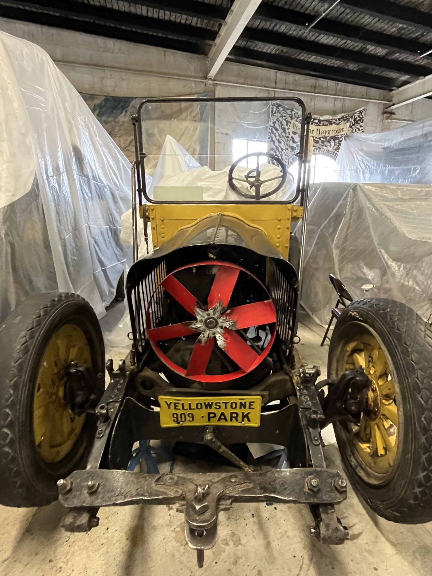 1917_YELL106383_Pic1 Historic vehicle parked in storage surrounded by protective tarp.
