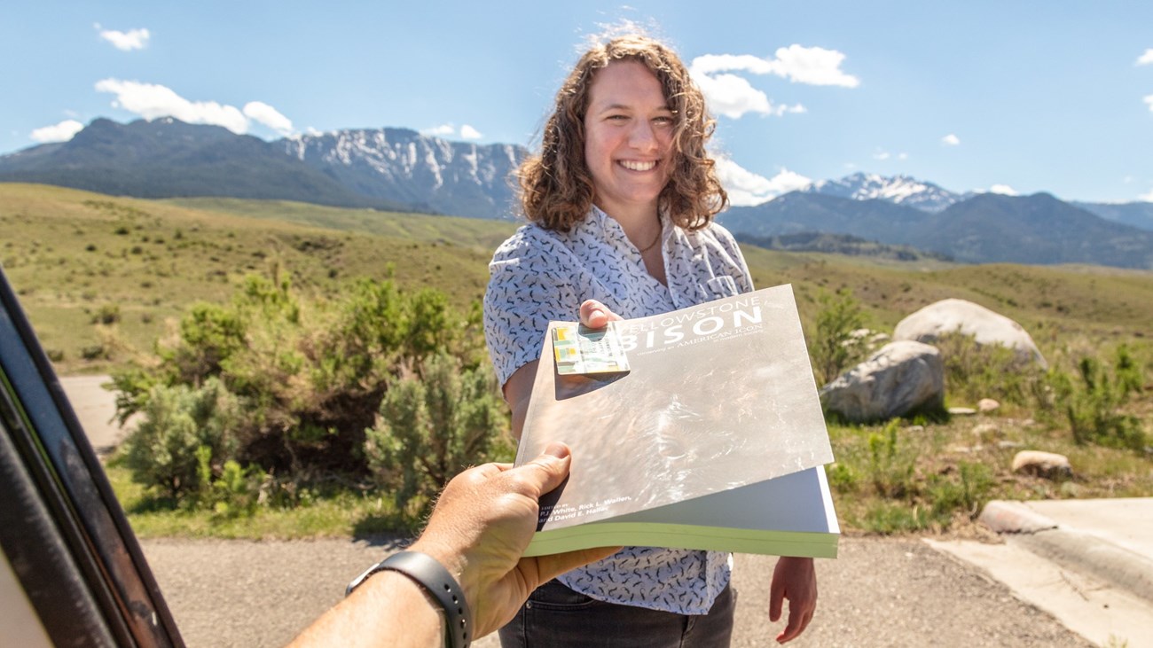 A person handing someone a book about bison