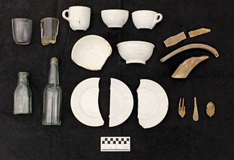 Artifacts on a black background, including glass bottles, plates, cups, and utensils