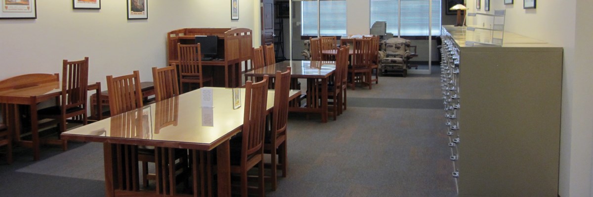 Empty glass-top tables with chairs in an open area with drawers on a wall Empty glass-top tables with chairs in an open area with drawers on a wall