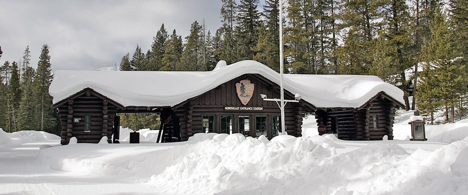 A log building with covered car lanes covered in snow