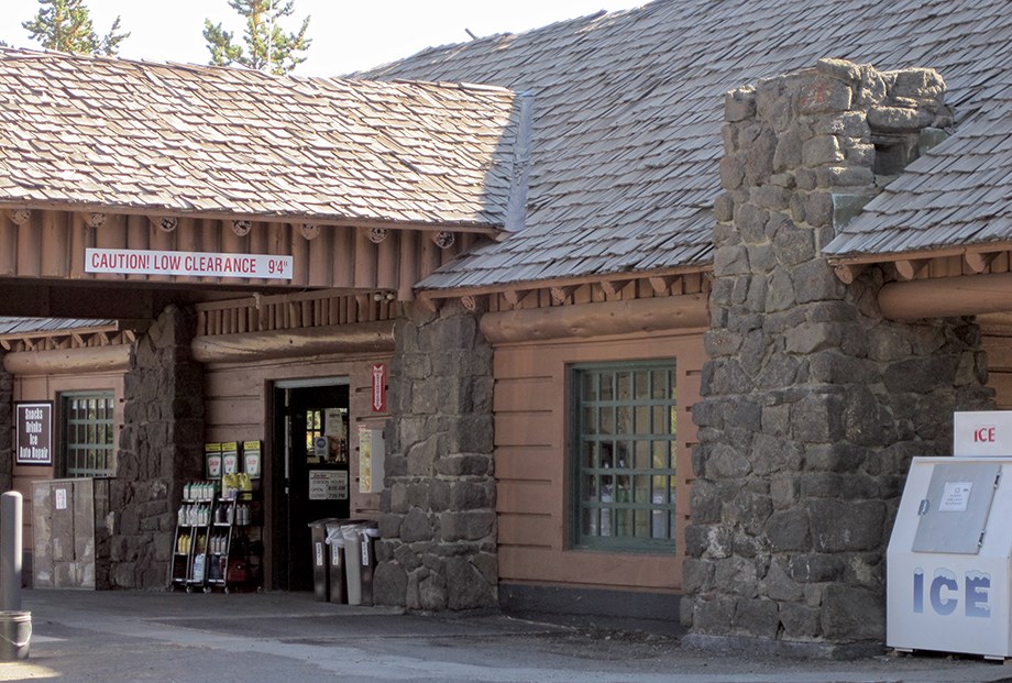 A log and stone structure with shingled roof and port cochere