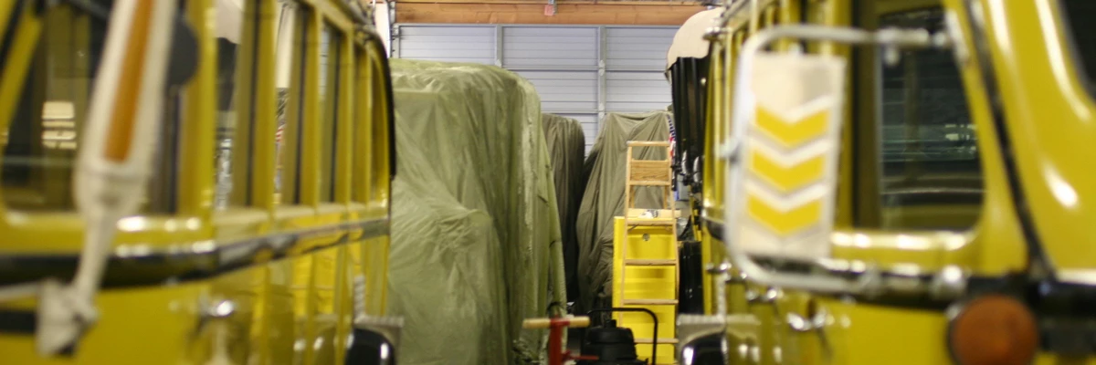 Historic Vehicle Collection garage Yellow historic vehicles at the front of a line of vehicles covered in drapes in a garage