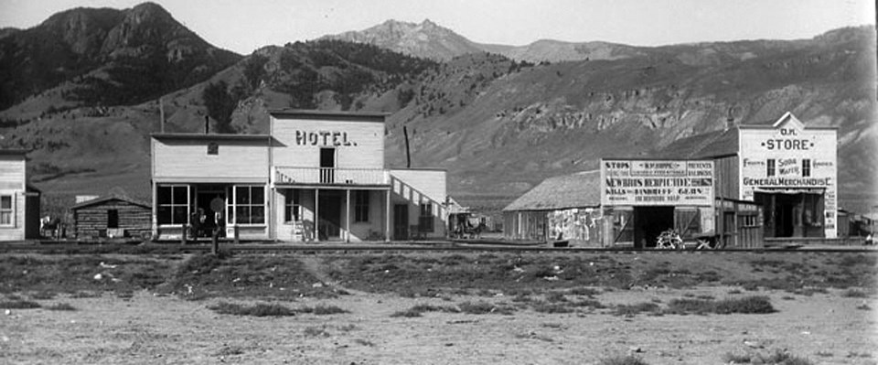 A historic photo of western town buildings in front of mountains A historic photo of western town buildings in front of mountains